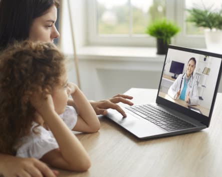 kid and her mother talking to their doctor via video call