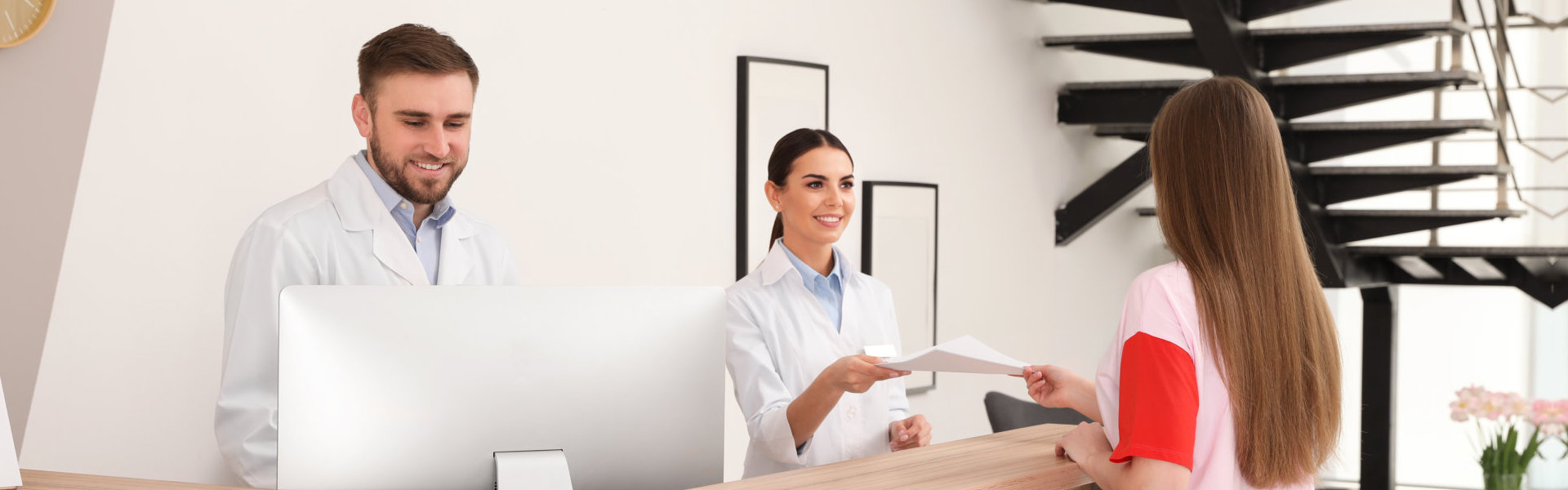 two doctor on front desk entertaining patients